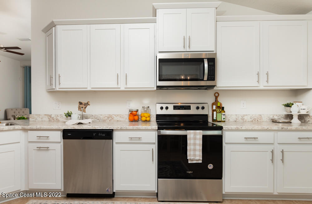 401 Scarlet Road Southwest Palm Bay, FL 32908 - Photo 7 of 24 a kitchen with granite countertop white cabinets and stainless steel appliances