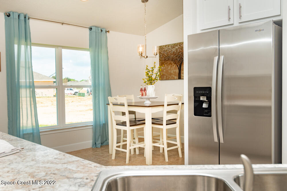 401 Scarlet Road Southwest Palm Bay, FL 32908 - Photo 9 of 24 a kitchen with a refrigerator a table and chairs in it