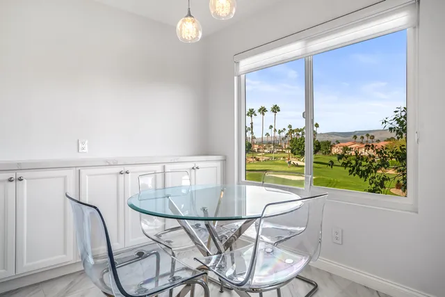 a view of a dining room with furniture one side kitchen view and wooden floor