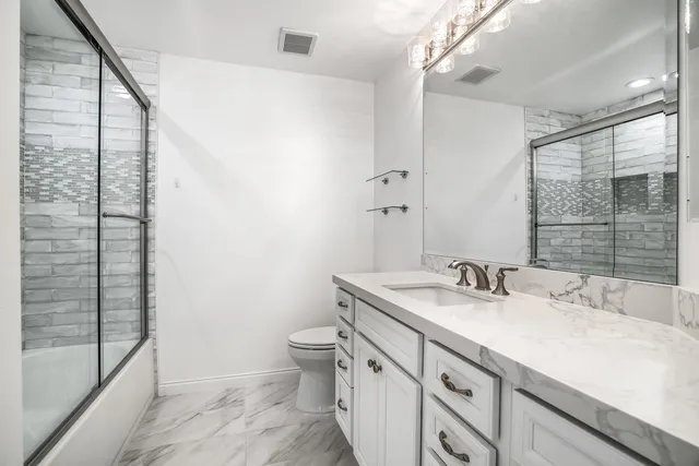 a bathroom with a granite countertop sink a toilet and shower