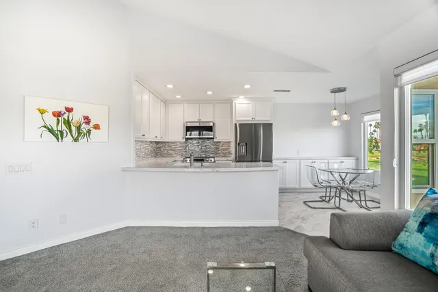 a living room with stainless steel appliances granite countertop furniture a couch a sink a rug and a window