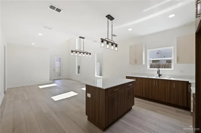 a kitchen with stainless steel appliances granite countertop a sink a stove a refrigerator and island with wooden floor