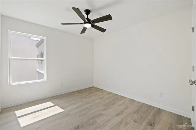an empty room with a window and a ceiling fan