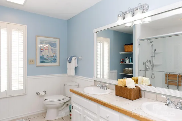 a bathroom with double vanity sinks a toilet and a mirror