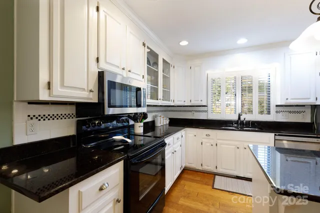 a kitchen with granite countertop a sink a stove and cabinets