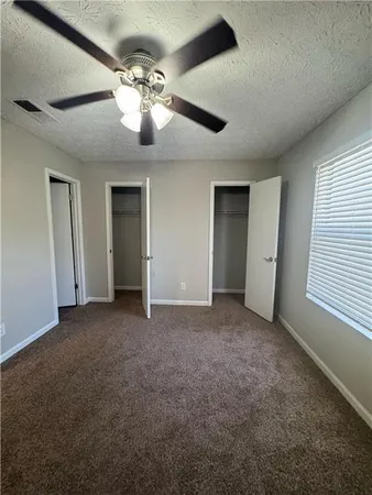 a view of an empty room with window and a kitchen