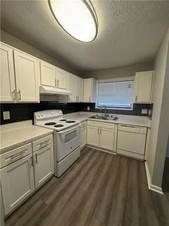a kitchen with cabinets a sink and white appliances