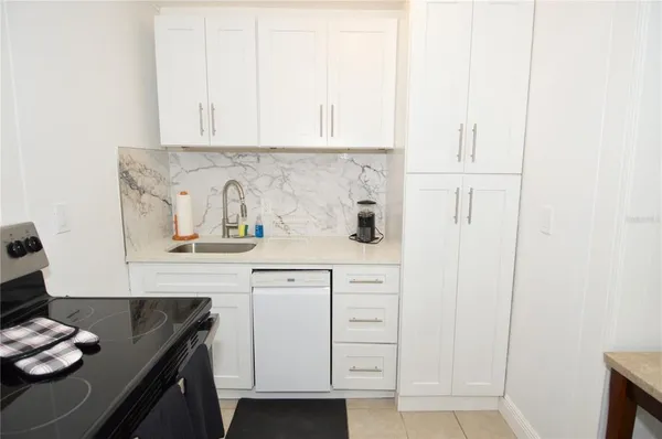 a kitchen with white cabinets and sink