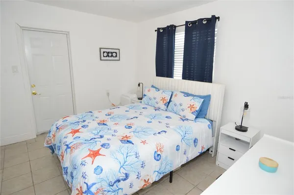 a bedroom with a bed and a lamp on the dresser