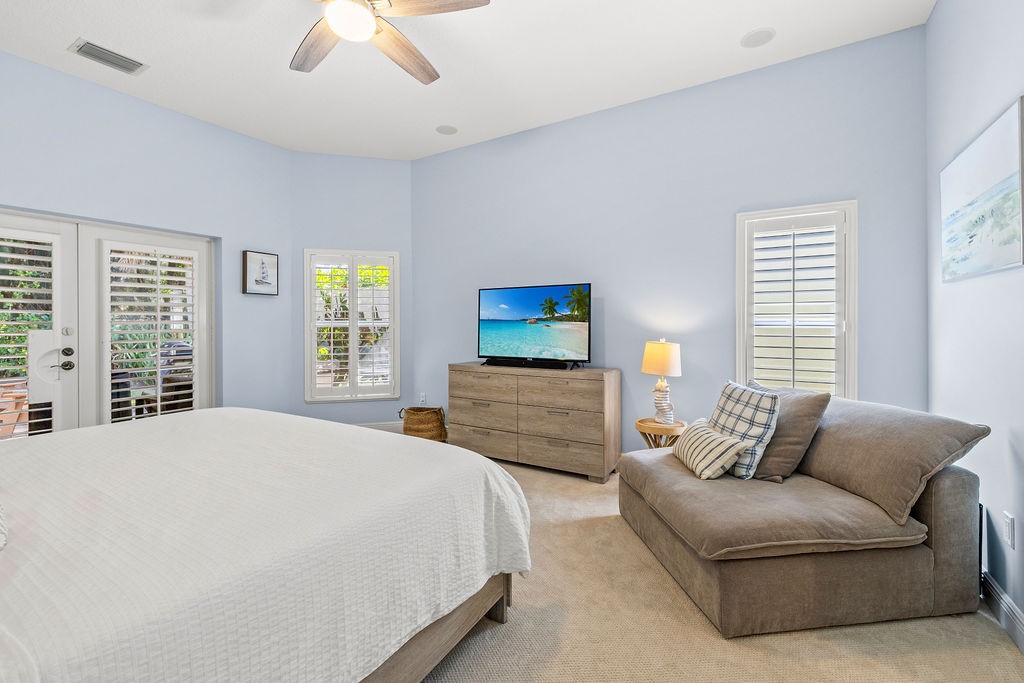 2134 Northwest Tilia Trail Stuart, FL 34994 - Photo 16 of 36 a bedroom with a bed a couch and a chandelier fan