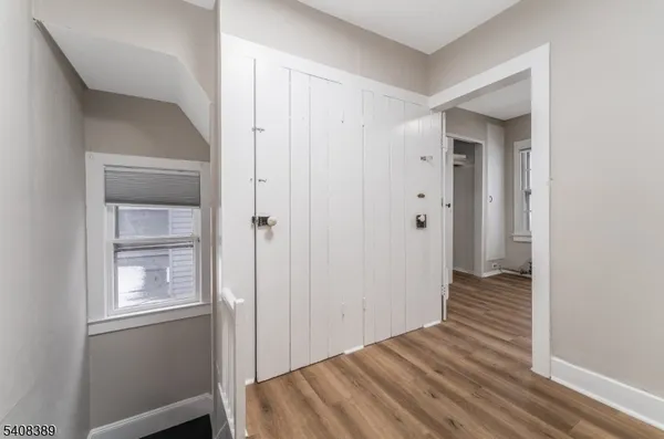 a view of a hallway with wooden floor and closet