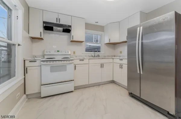 a kitchen with white cabinets stainless steel appliances and a refrigerator