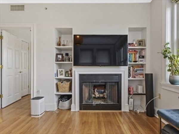 2025 Commonwealth Avenue, Unit 5 Boston, MA 02135 - Photo 4 of 13 a living room with a fireplace and a wooden floor