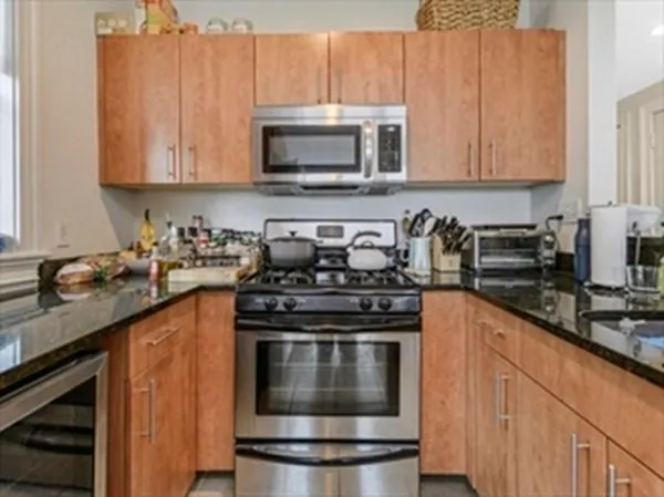 a kitchen with granite countertop a stove top oven microwave and cabinets