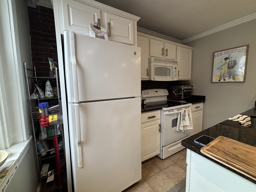 41 Grove Boston Ma, Unit 4 Boston, MA 02114 - Photo 7 of 20 a kitchen with white cabinets and refrigerator
