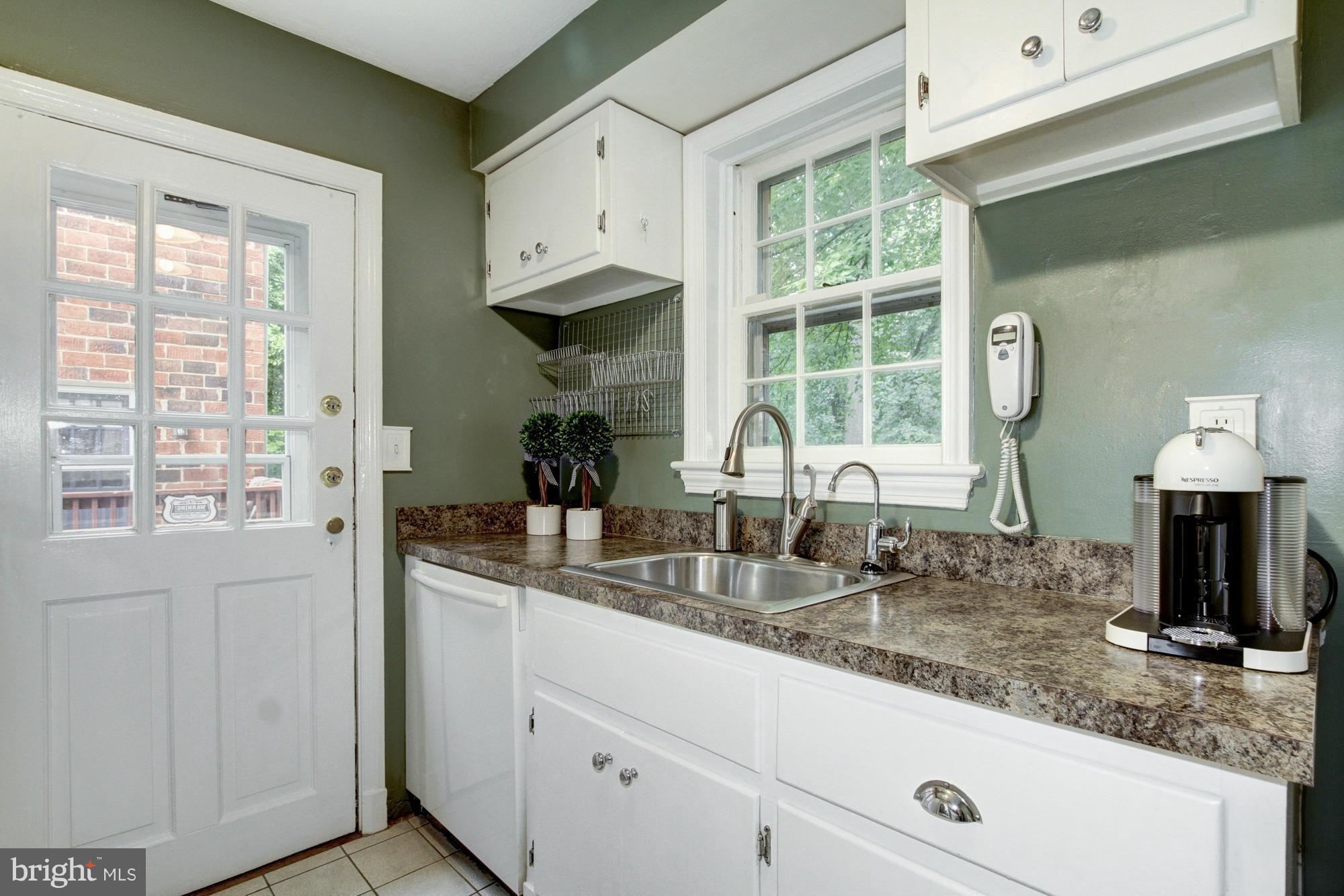9917 Big Rock Road Silver Spring, MD 20901 - Photo 9 of 24 a kitchen with granite countertop a sink white cabinets and a window