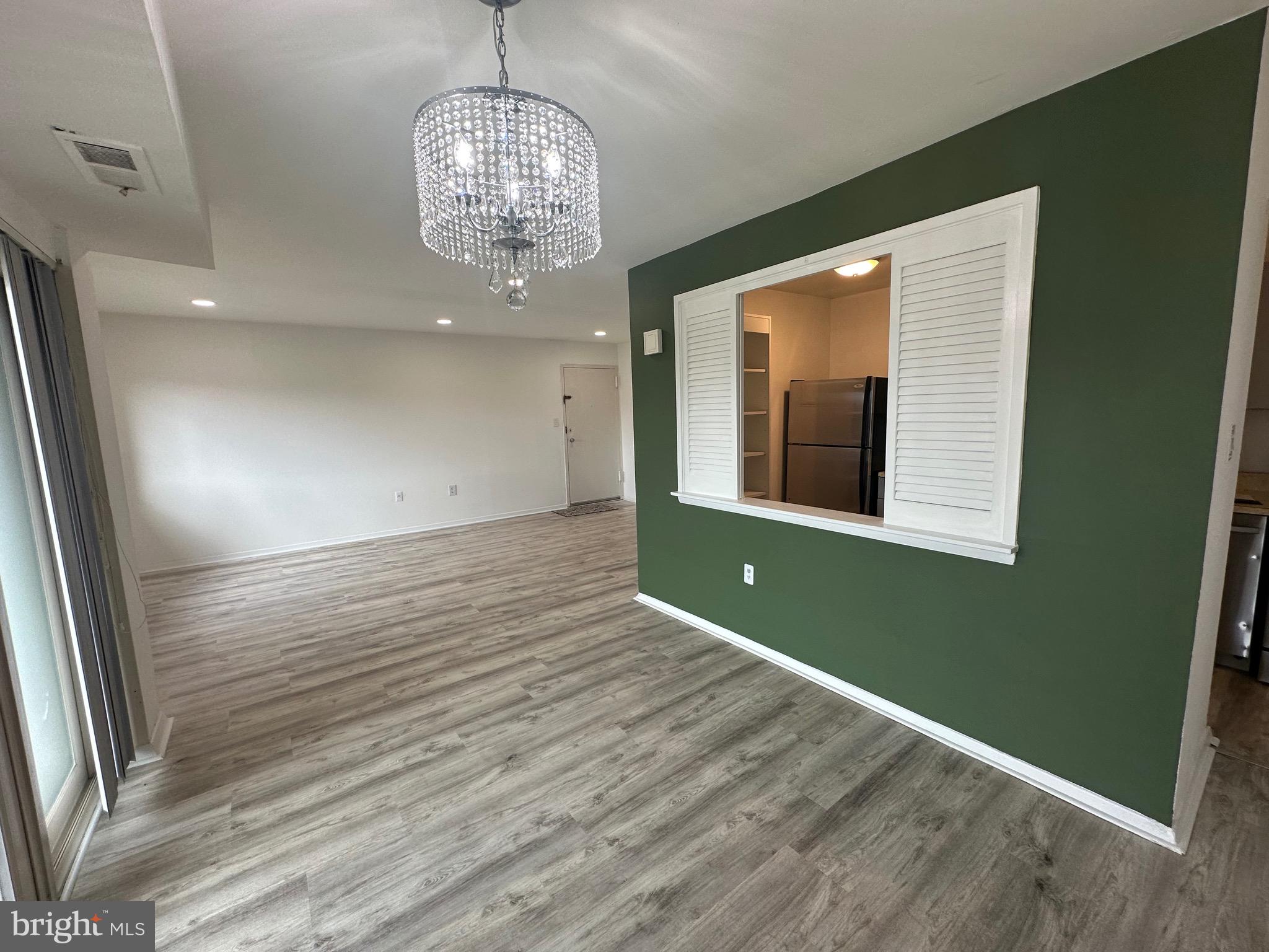 3722 Bel Pre Road, Unit 12 Silver Spring, MD 20906 - Photo 8 of 26 an empty room with wooden floor chandelier and windows