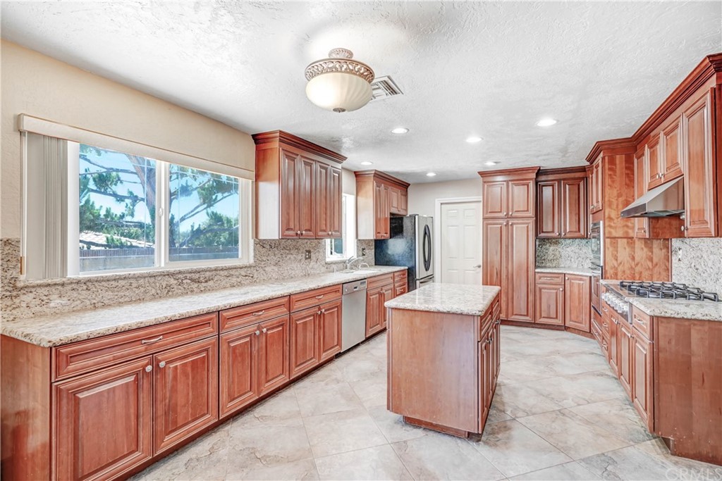 a large kitchen with kitchen island granite countertop a large counter top space a sink stainless steel appliances and cabinets