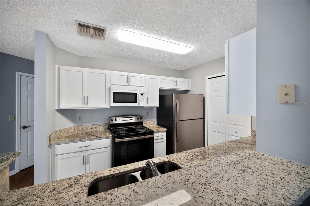 96025 Sunfish Lane Yulee, FL 32097 - Photo 8 of 17 a kitchen with a refrigerator stove and white cabinets
