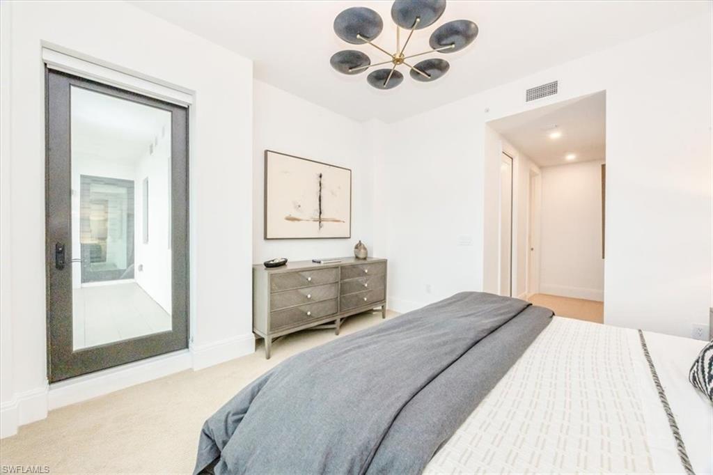 1130 3rd Avenue South, Unit 416 Naples, FL 34102 - Photo 33 of 49 a bedroom with a large bed and a chandelier