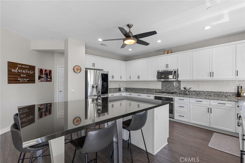 19512 Griffith Drive Saugus, CA 91350 - Photo 11 of 46 a kitchen with stainless steel appliances granite countertop a sink a stove a refrigerator a island with chairs and wooden floor