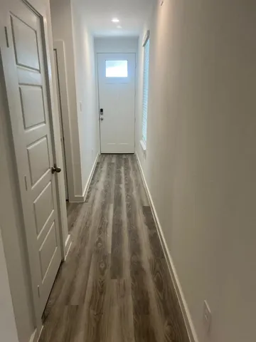 a view of a hallway with wooden floor and a bathroom
