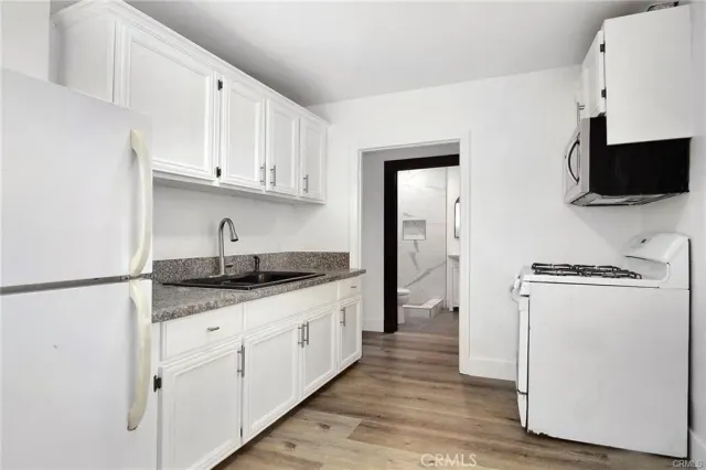 a kitchen with stainless steel appliances granite countertop a refrigerator sink and white cabinets