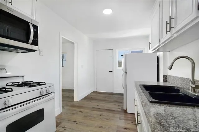 a kitchen with granite countertop cabinets stainless steel appliances and wooden floor
