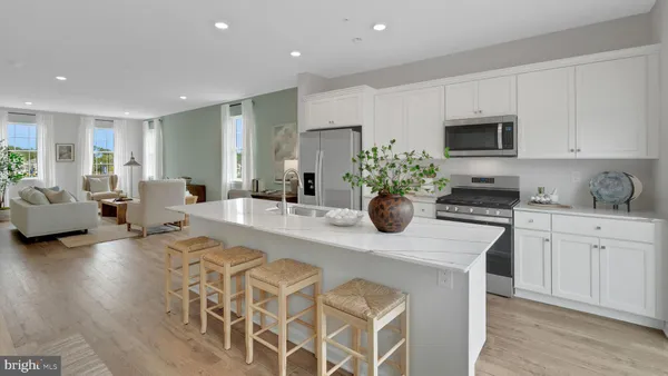 a kitchen with stainless steel appliances kitchen island granite countertop a sink dishwasher stove and white cabinets with wooden floor