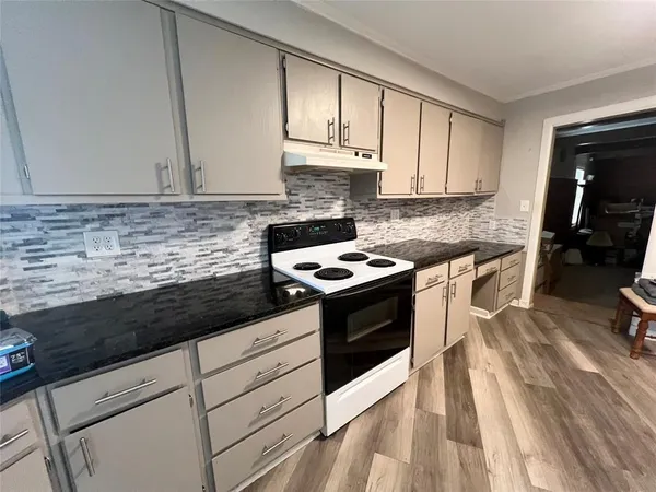 a kitchen with granite countertop cabinets stainless steel appliances and a wooden floor