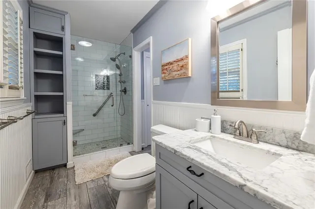 a bathroom with a granite countertop sink a toilet a shower and a mirror