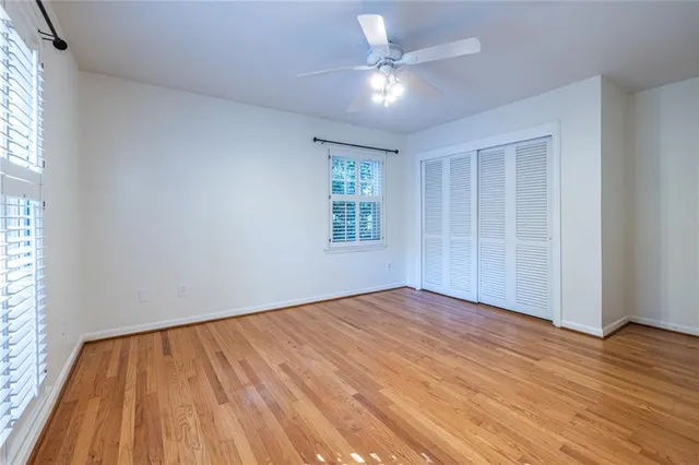 an empty room with wooden floor chandelier fan and windows