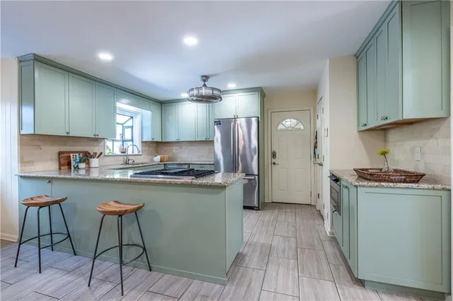 a kitchen with stainless steel appliances granite countertop a stove a sink a refrigerator and cabinets