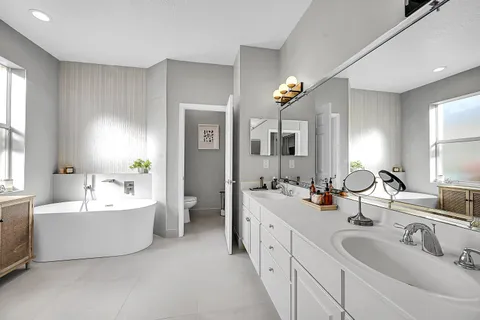 a bathroom with double vanity sinks a large mirror and a bathtub
