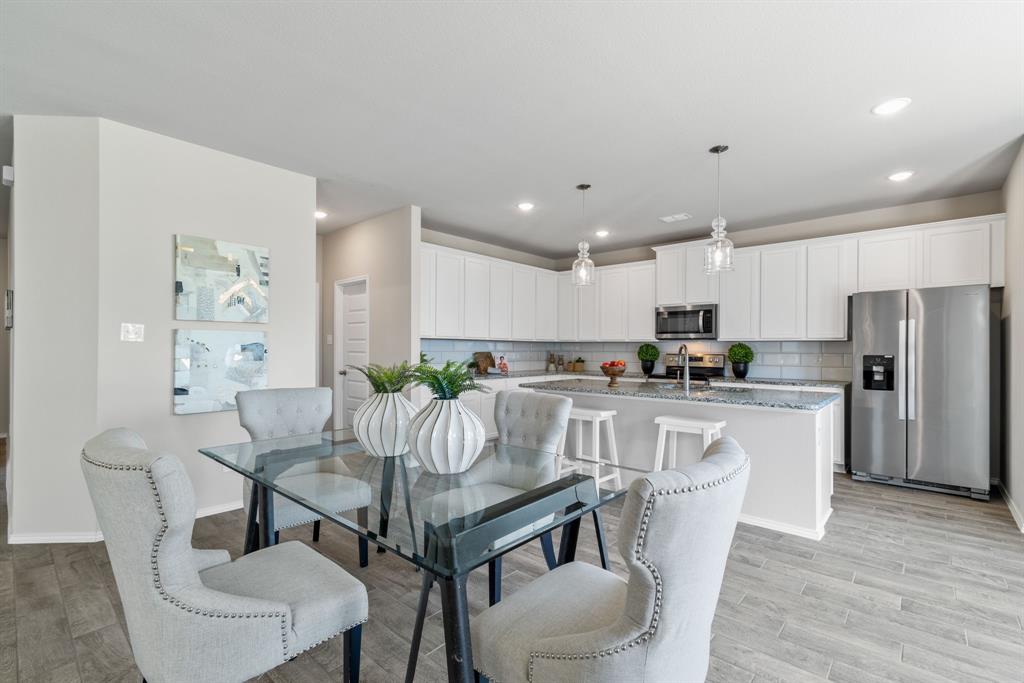 a kitchen with stainless steel appliances granite countertop a white table and chairs