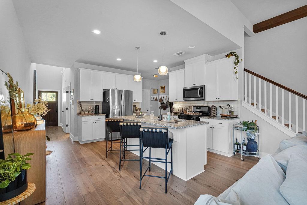 1201 Shiva Boulevard Winder, GA 30680 - Photo 34 of 84 a kitchen with stainless steel appliances kitchen island granite countertop a refrigerator a stove top oven a sink dishwasher and white cabinets with wooden floor