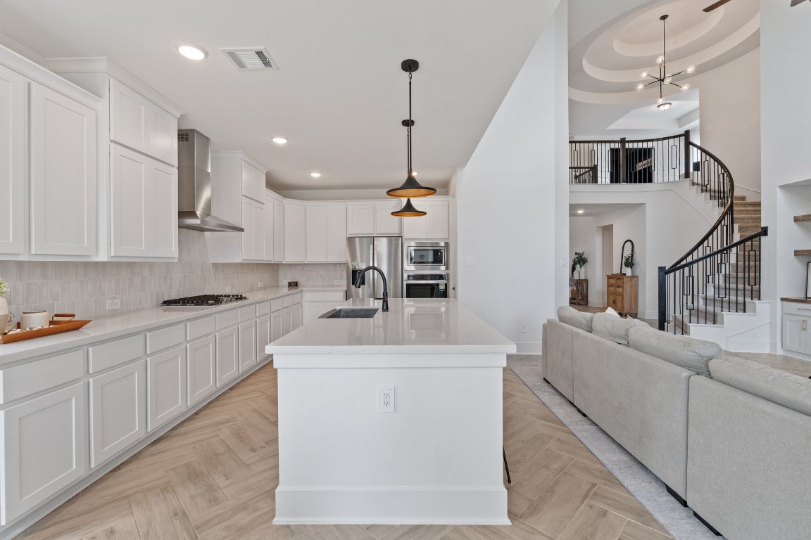 914 Sendero Trail Conroe, TX 77304 - Photo 11 of 50 a large white kitchen with kitchen island a sink a center island stainless steel appliances and a chandelier