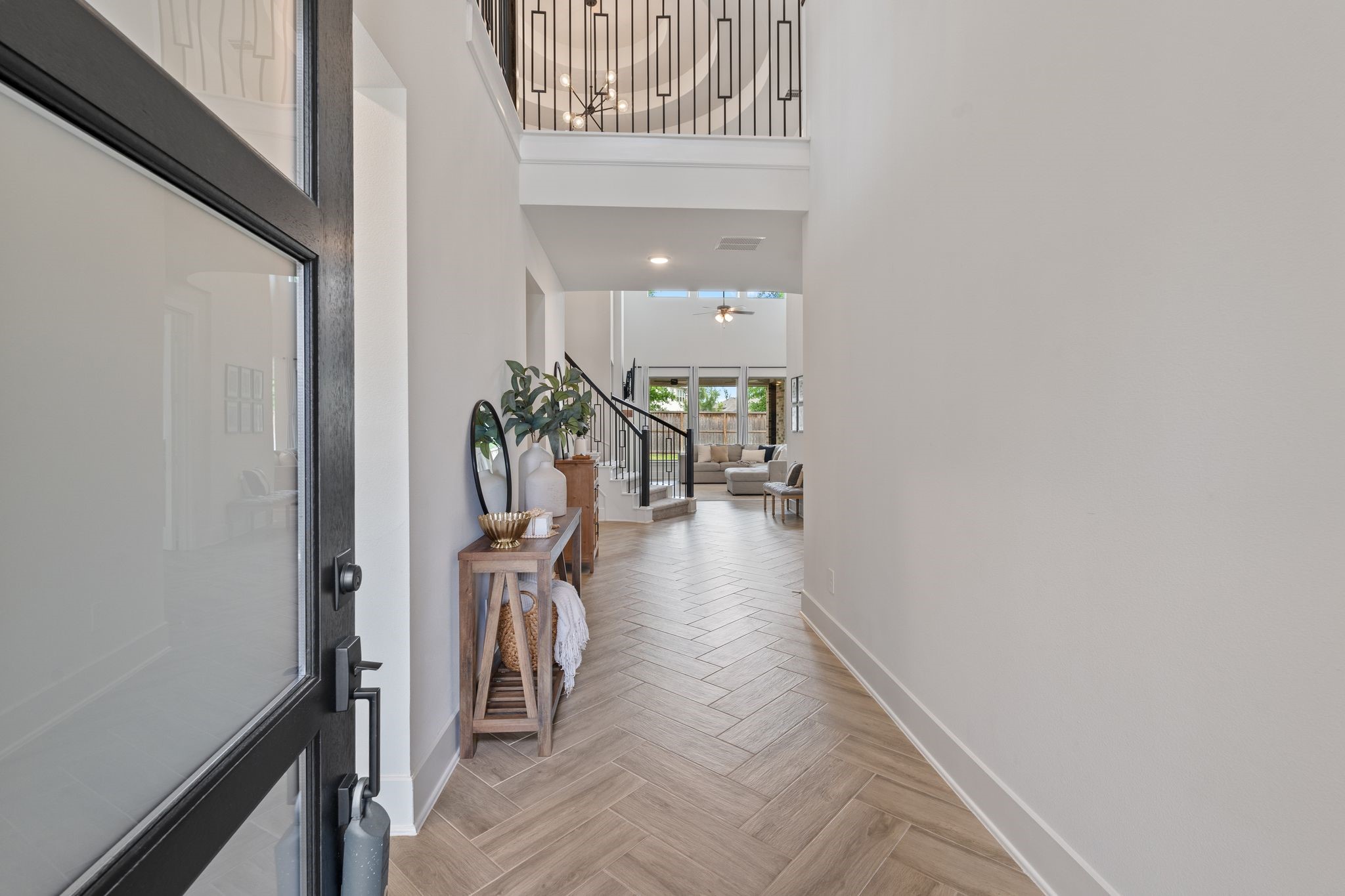 914 Sendero Trail Conroe, TX 77304 - Photo 3 of 47 Bright and airy entryway with light wood herringbone flooring, crisp white walls, and a modern front door.