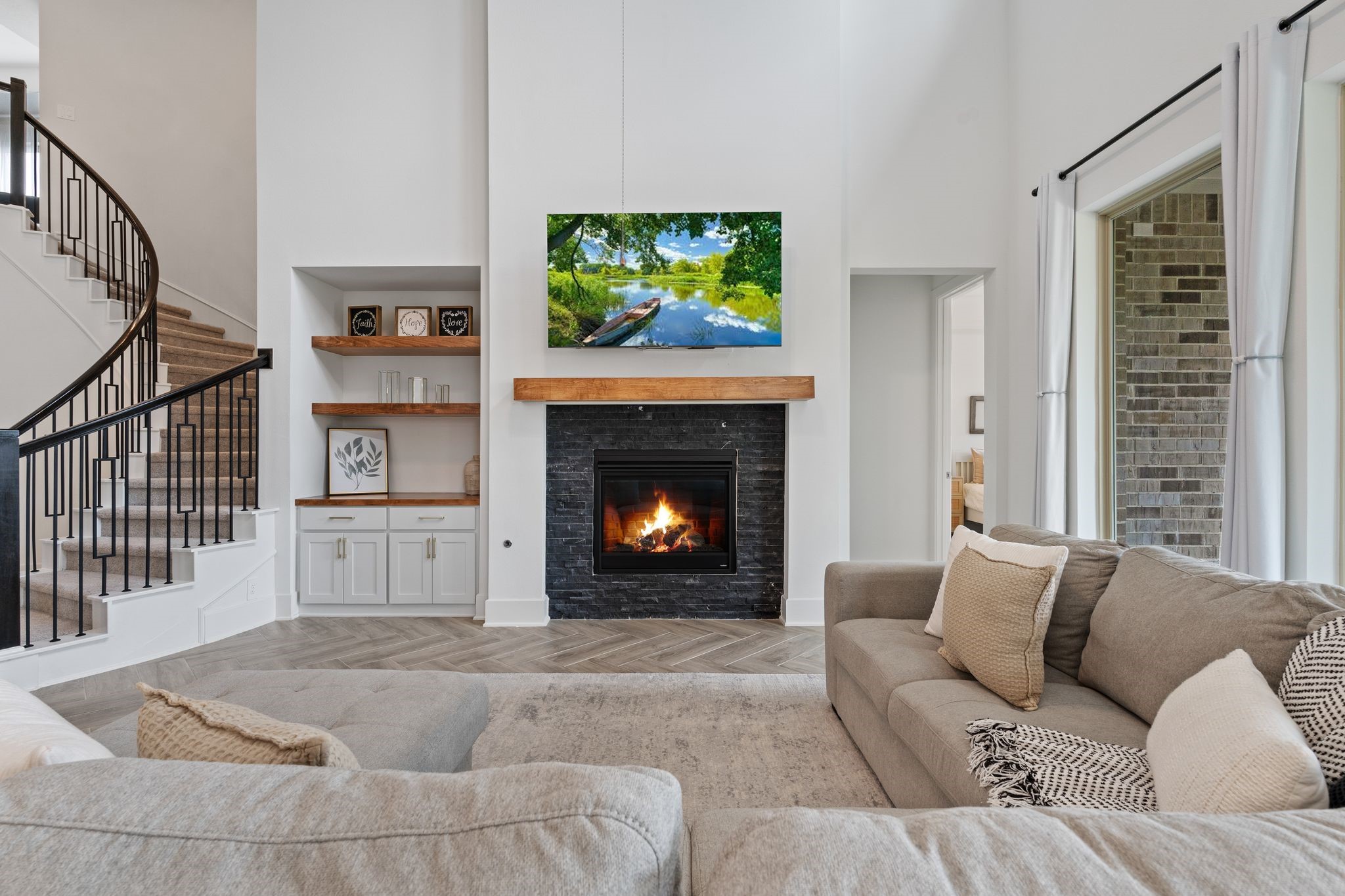 914 Sendero Trail Conroe, TX 77304 - Photo 7 of 47 Bright and open living room features a modern fireplace with dark tile surround and wood mantel. Beautiful built-ins and the sweeping curved staircase create a warm and inviting space.
