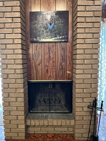 1085 West Elk Road Helper, UT 84526 - Photo 17 of 40 Brick fireplace with a metal fire screen, a brick hearth, and a wood-finish accent wall