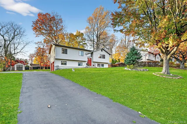 a view of a white house with a big yard plants and large trees