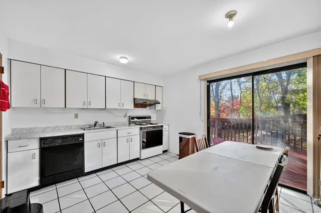 a kitchen with stainless steel appliances granite countertop a stove a sink dishwasher a refrigerator with white cabinets and wooden floor