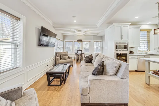 a living room with furniture a flat screen tv and kitchen view