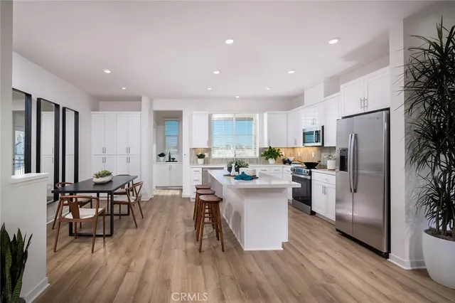 a kitchen with stainless steel appliances a dining table chairs stove refrigerator and cabinets