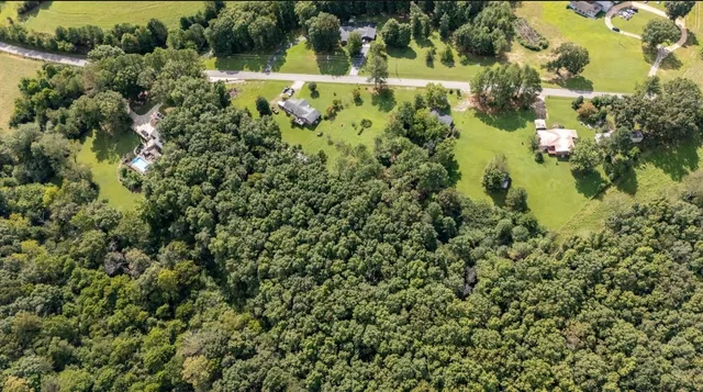 an aerial view of residential house with outdoor space and trees all around