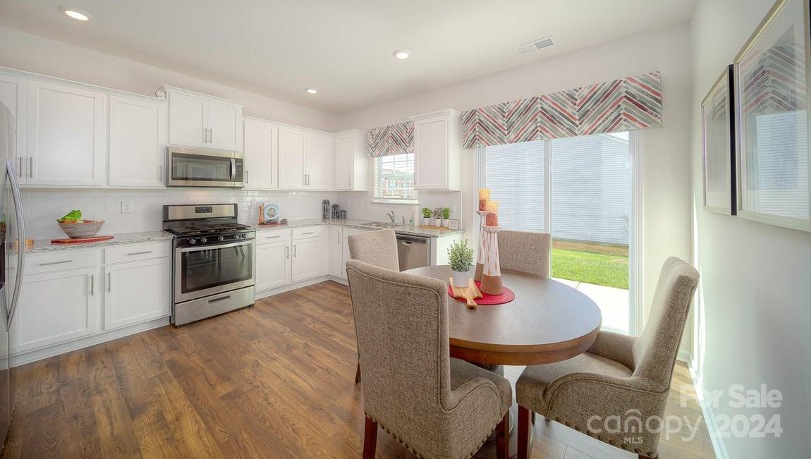 3627 Azalea Rdg Drive Mount Holly, NC 28120 - Photo 11 of 34 a kitchen with stainless steel appliances granite countertop a refrigerator a stove a sink dishwasher and a dining table with wooden floor