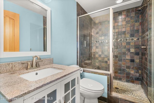 a bathroom with a granite countertop sink toilet and shower