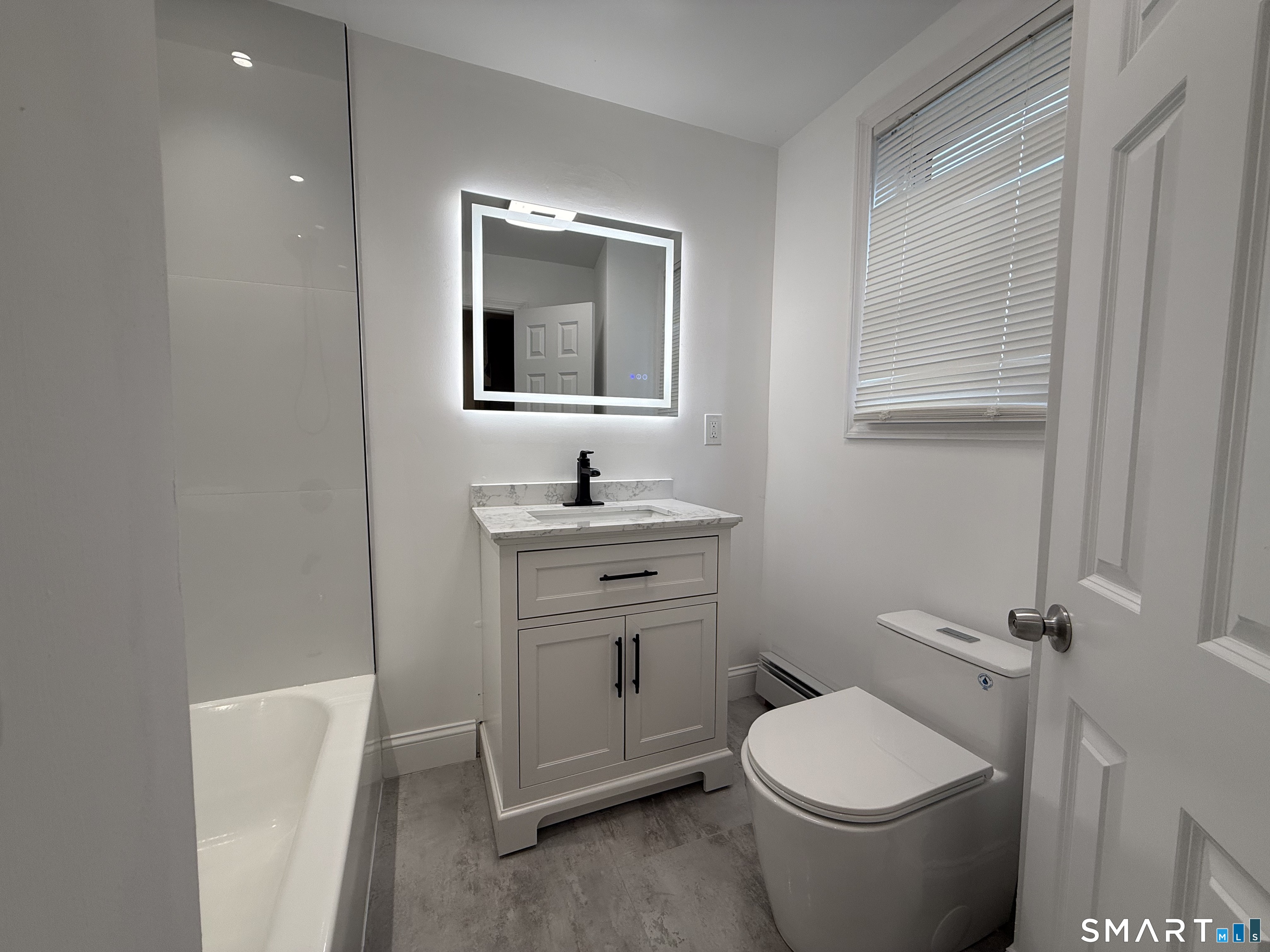a bathroom with a toilet a sink a mirror and vanity