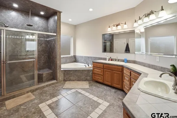 a spacious bathroom with a sink a large mirror and a bathtub