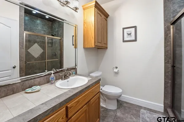 a bathroom with a granite countertop sink toilet and mirror